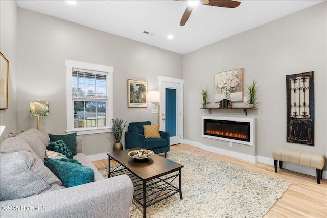 living room with recessed lighting, wood finished floors, visible vents, baseboards, and a glass covered fireplace