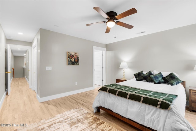 bedroom with light wood-style floors, visible vents, baseboards, and a ceiling fan