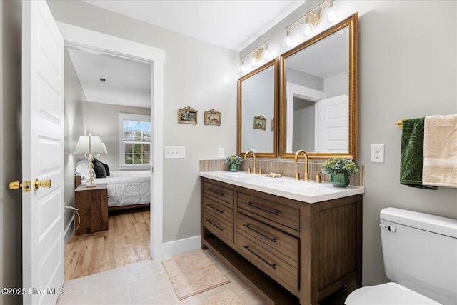 full bath featuring double vanity, a sink, toilet, and ensuite bathroom