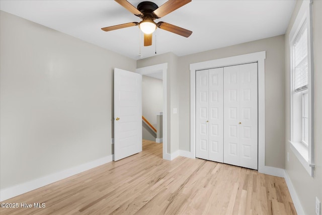 unfurnished bedroom featuring baseboards, ceiling fan, a closet, and light wood-style floors