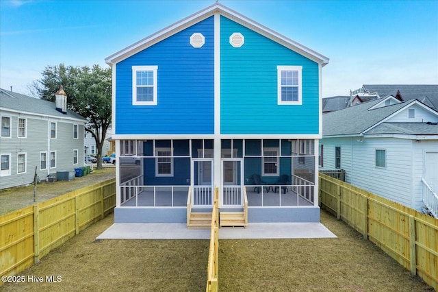 back of house with a sunroom, a fenced backyard, a lawn, and central AC