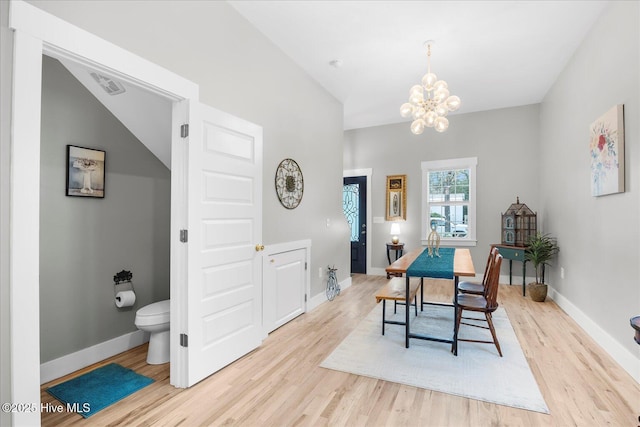 dining space featuring a notable chandelier, visible vents, baseboards, vaulted ceiling, and light wood finished floors