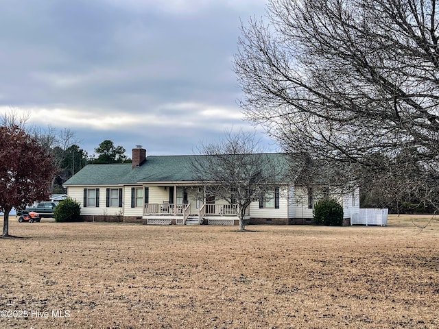 ranch-style house featuring a chimney, covered porch, crawl space, and a front yard