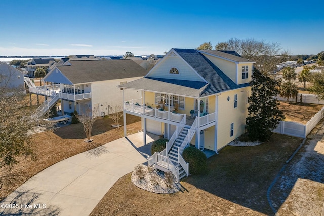 back of property featuring stairway, a residential view, covered porch, concrete driveway, and an attached garage