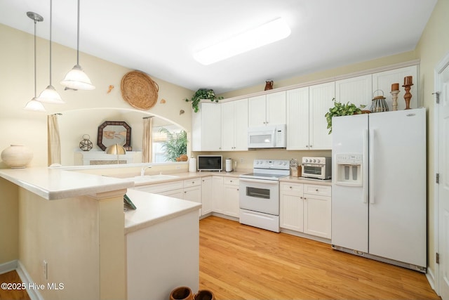 kitchen with light wood finished floors, decorative light fixtures, a peninsula, white appliances, and white cabinetry