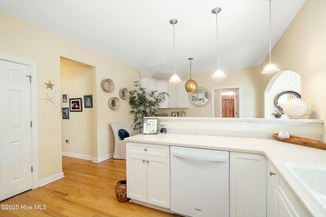 kitchen with light wood-style flooring, decorative light fixtures, white cabinets, white dishwasher, and light countertops