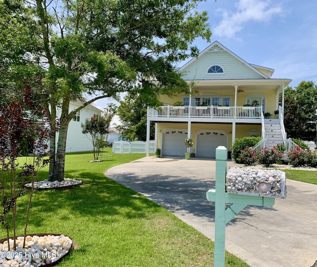 coastal home featuring a front lawn, stairs, covered porch, a garage, and driveway