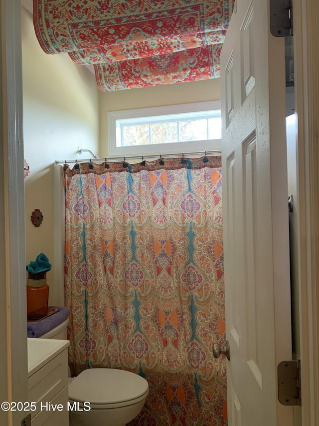 full bath featuring a shower with curtain, toilet, and vanity