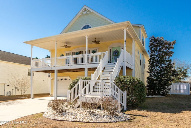 coastal inspired home featuring stairway, a ceiling fan, a porch, an attached garage, and concrete driveway