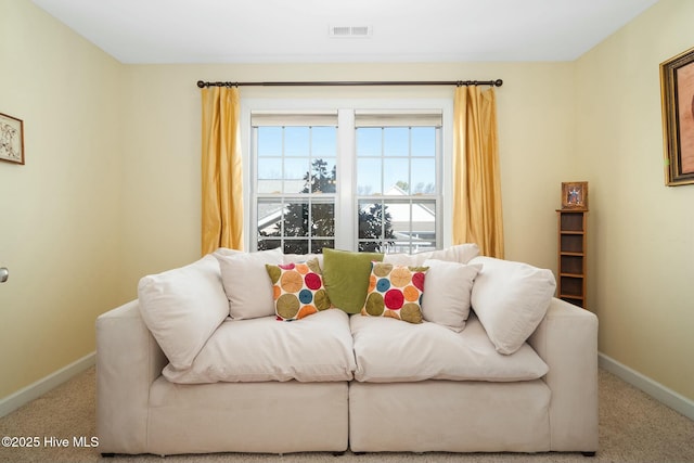 carpeted living area featuring visible vents and baseboards