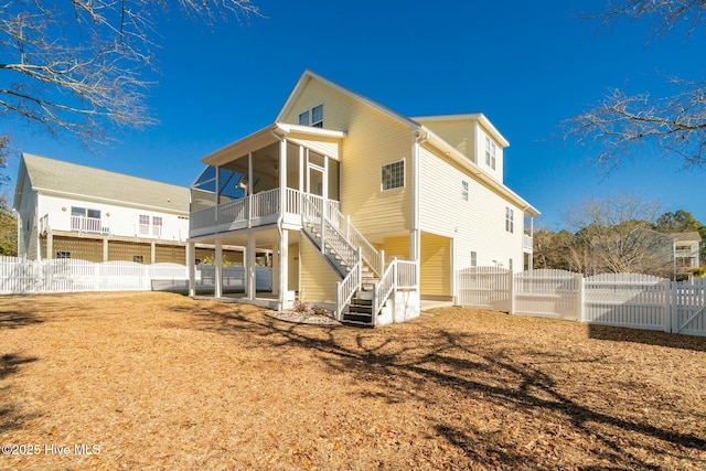 back of property with a gate, stairs, a fenced backyard, and a sunroom