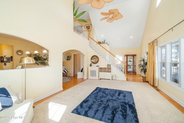 living room featuring stairway, wood finished floors, arched walkways, and ceiling fan