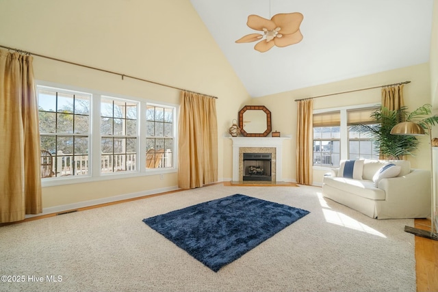 carpeted living area featuring visible vents, baseboards, a tile fireplace, high vaulted ceiling, and a ceiling fan