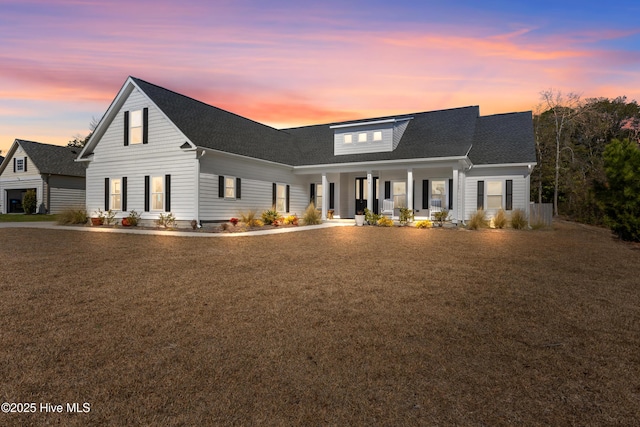 view of front of house with roof with shingles, a porch, and a front yard