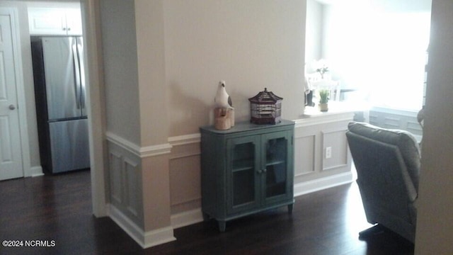 home office with a wainscoted wall, dark wood-type flooring, and a decorative wall