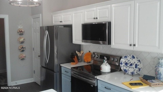 kitchen with baseboards, stainless steel appliances, light countertops, white cabinetry, and backsplash