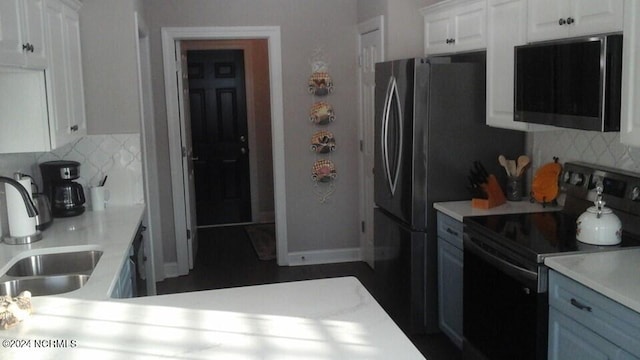 kitchen with range with electric stovetop, tasteful backsplash, light countertops, white cabinets, and a sink