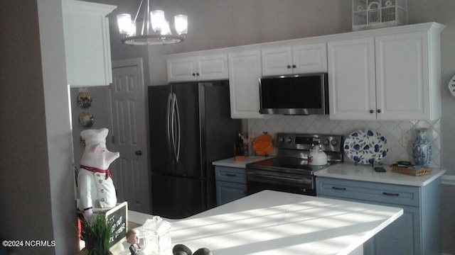 kitchen featuring white cabinets, appliances with stainless steel finishes, light countertops, and decorative light fixtures