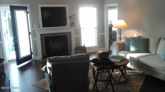 living area featuring a fireplace with flush hearth, dark wood finished floors, and a healthy amount of sunlight