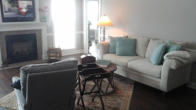 living area featuring dark wood-type flooring, baseboards, and a fireplace with flush hearth