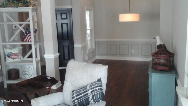 sitting room with dark wood-style floors, a decorative wall, and wainscoting