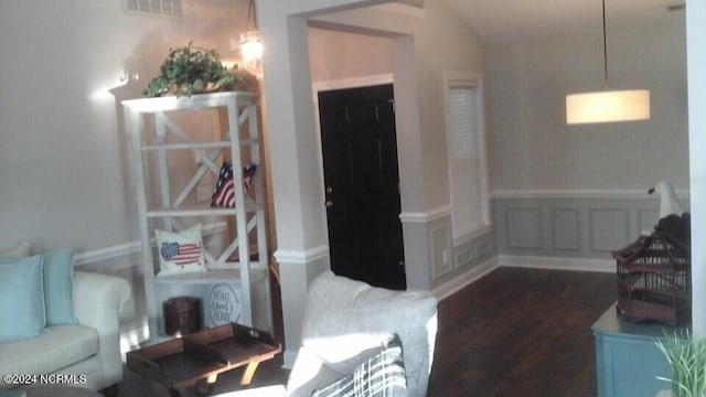 living area with lofted ceiling, visible vents, dark wood-type flooring, and wainscoting