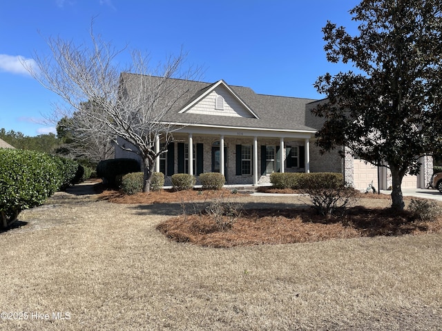 greek revival house featuring covered porch, brick siding, roof with shingles, and a garage