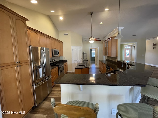 kitchen featuring a center island with sink, a breakfast bar area, stainless steel appliances, lofted ceiling, and a sink