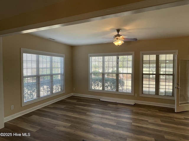 unfurnished room featuring a healthy amount of sunlight, dark wood-style floors, and baseboards