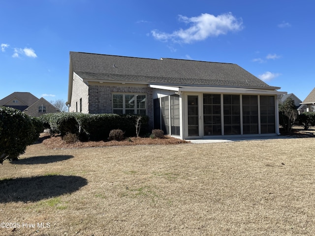 rear view of house featuring brick siding and a sunroom