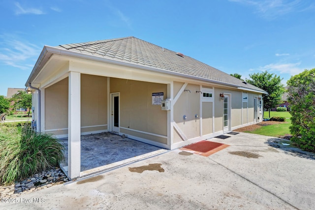 exterior space featuring a shingled roof, a patio, and stucco siding