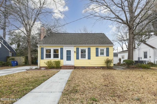 bungalow-style home with crawl space, roof with shingles, a chimney, and a front yard