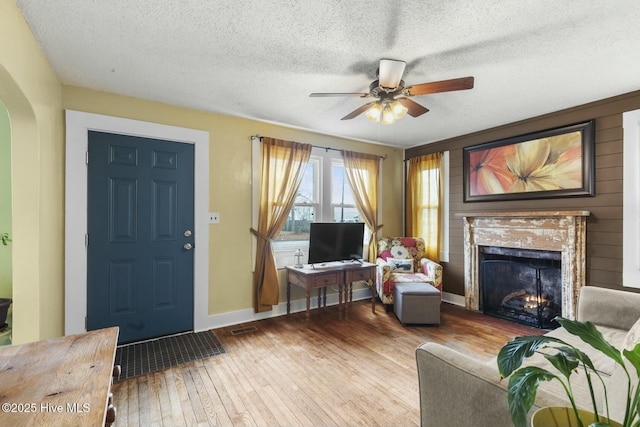 interior space with baseboards, arched walkways, a premium fireplace, wood finished floors, and a textured ceiling