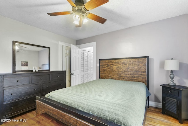 bedroom with a textured ceiling, light wood finished floors, a ceiling fan, and baseboards