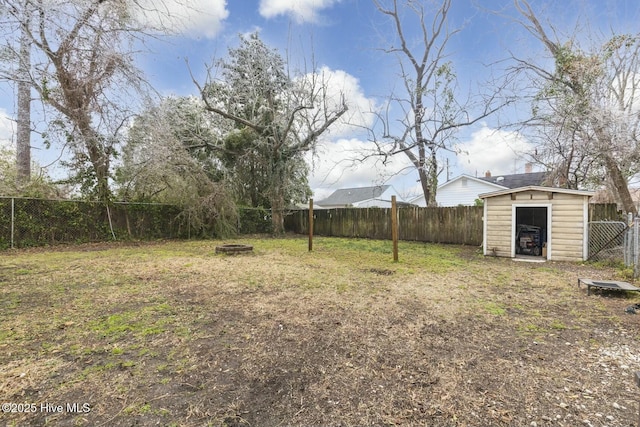 view of yard featuring an outdoor fire pit, a fenced backyard, an outbuilding, and a storage shed