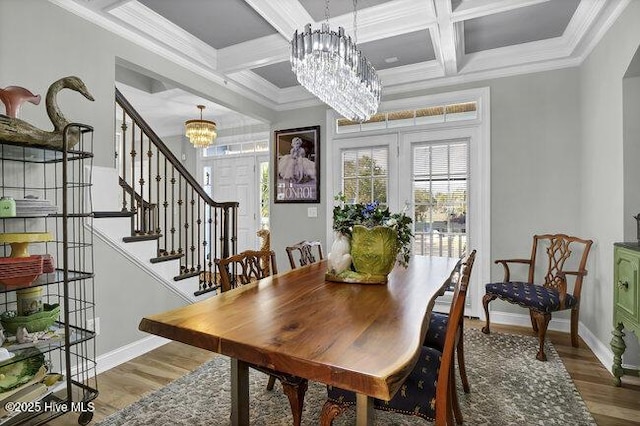 dining space with a chandelier, ornamental molding, coffered ceiling, and wood finished floors