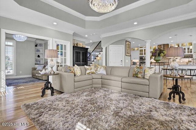 living room featuring recessed lighting, a notable chandelier, light wood-style floors, ornamental molding, and ornate columns