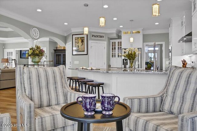 kitchen featuring white cabinets, glass insert cabinets, light stone counters, light wood-type flooring, and pendant lighting