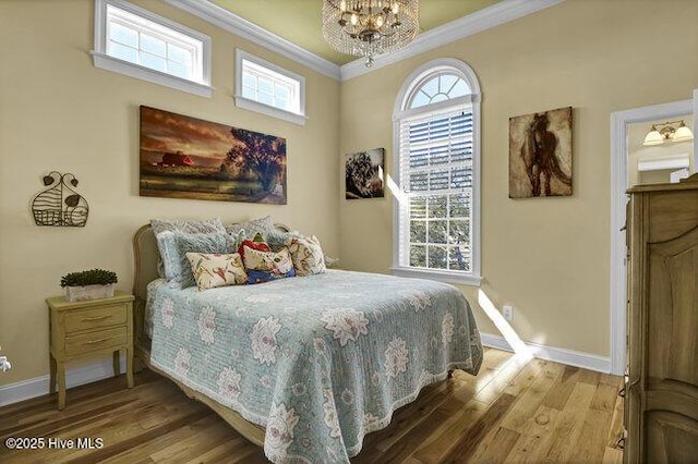 bedroom featuring baseboards, multiple windows, wood finished floors, and crown molding