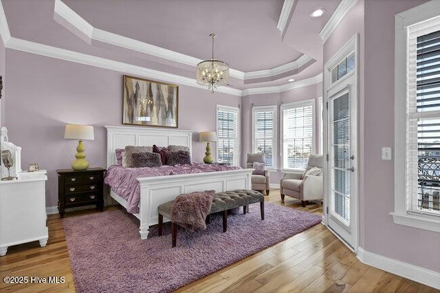 bedroom featuring crown molding, a tray ceiling, wood finished floors, and baseboards