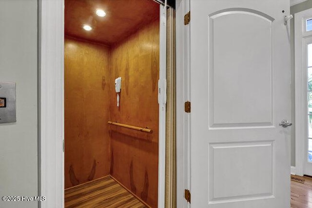 interior details featuring elevator, visible vents, and wood finished floors