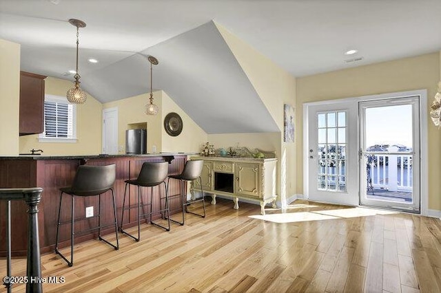 bar featuring decorative light fixtures, light wood finished floors, freestanding refrigerator, vaulted ceiling, and baseboards