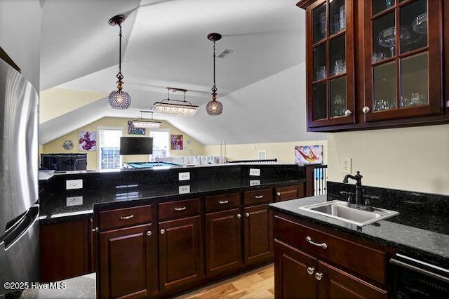 kitchen with glass insert cabinets, lofted ceiling, decorative light fixtures, and a sink