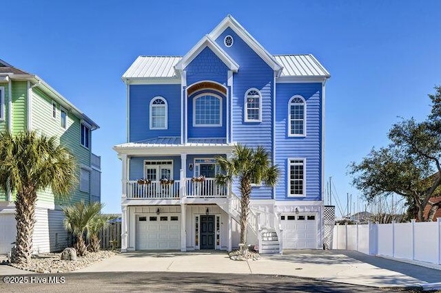 raised beach house with metal roof, a porch, concrete driveway, and fence