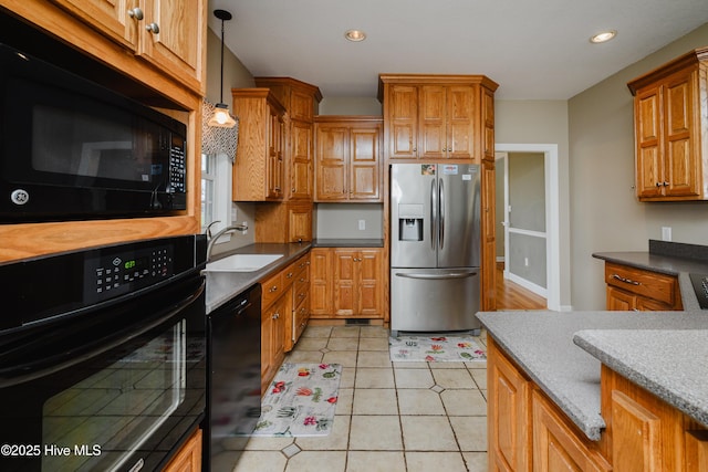 kitchen with brown cabinets, decorative light fixtures, light tile patterned flooring, a sink, and black appliances