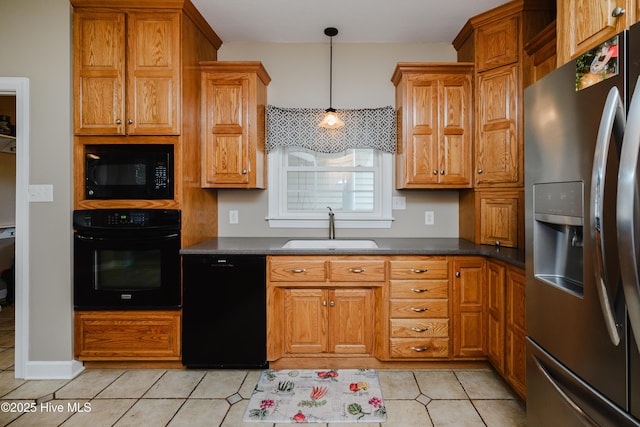 kitchen featuring dark countertops, brown cabinets, a sink, and black appliances