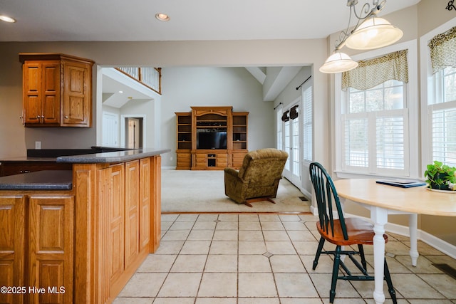 kitchen featuring dark countertops, brown cabinets, open floor plan, hanging light fixtures, and recessed lighting