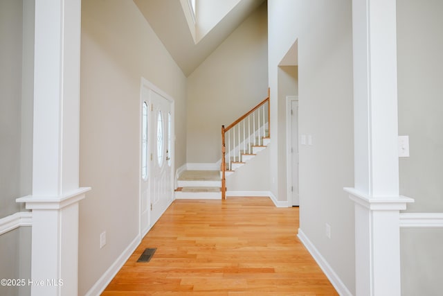 entrance foyer with high vaulted ceiling, wood finished floors, visible vents, baseboards, and stairway