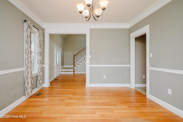 unfurnished room with an inviting chandelier, baseboards, stairway, and wood finished floors