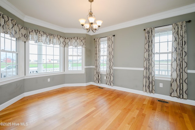 unfurnished dining area featuring visible vents, an inviting chandelier, wood finished floors, plenty of natural light, and baseboards